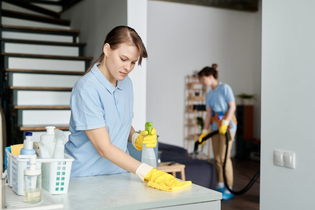 Cleaning service worker wiping dust from furniture